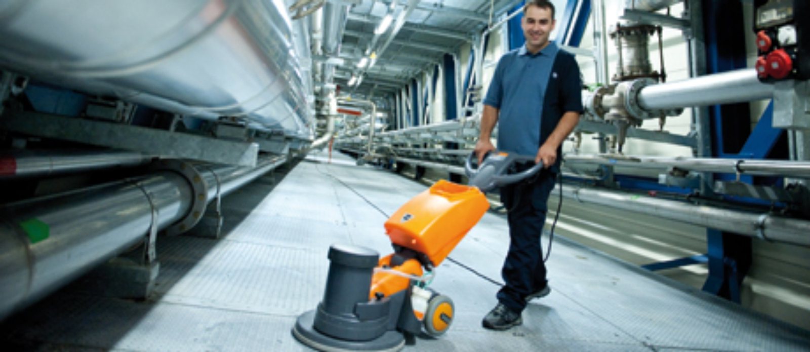 Reinigungskraft mit Maschine in einer Industriehalle